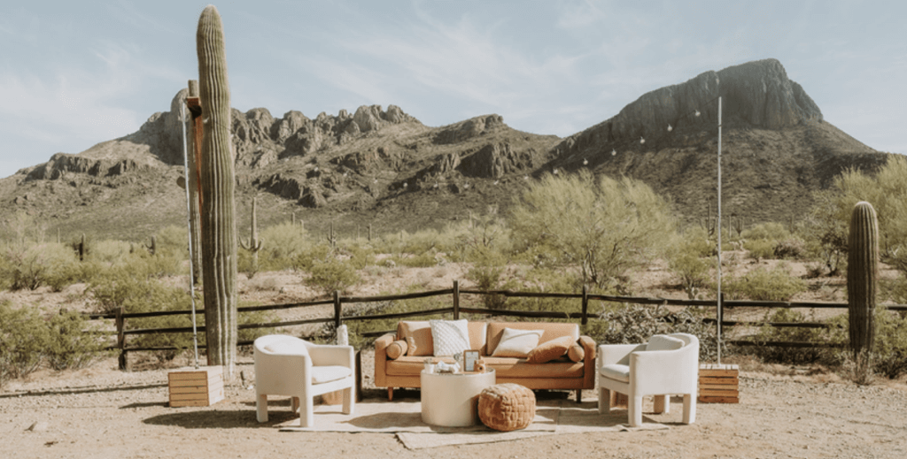 a couch and chairs with western themed decorations that have been placed along a fence at a desert ranch in tucson