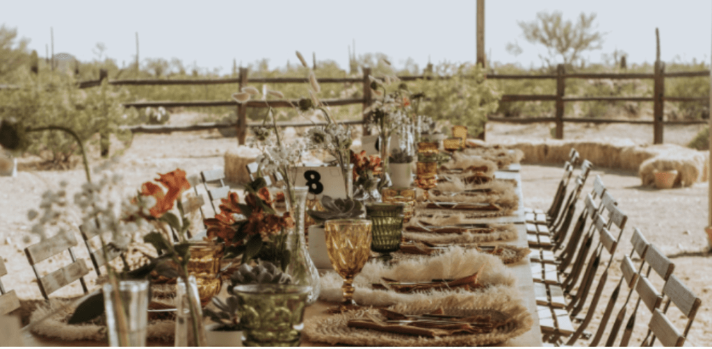 colorful glasses, candles, and western themed centerpiece decorations lining a table that's set up for a wedding at a dude ranch in tucson