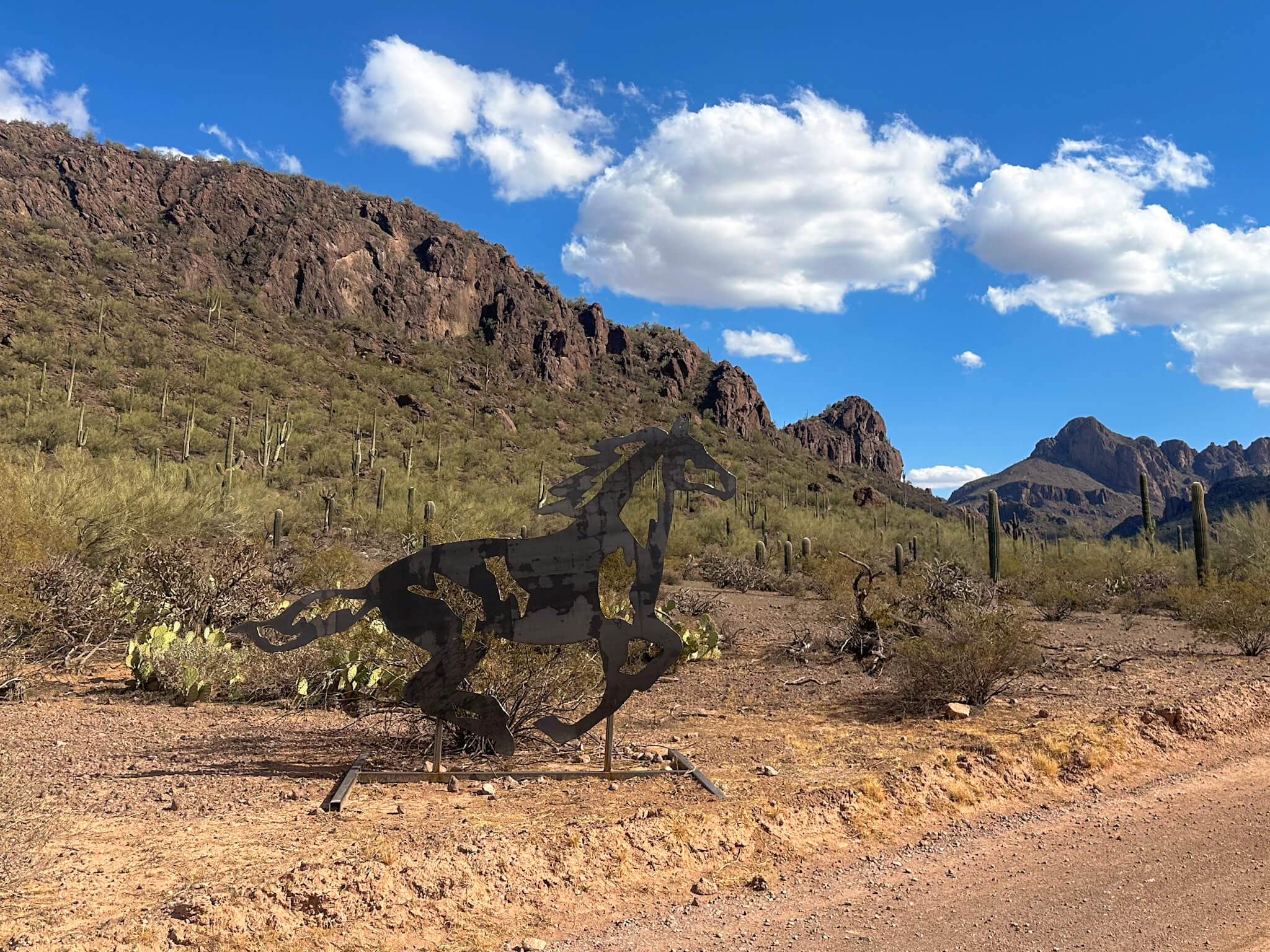 metal horse set in front of tucson mountains mid day sun and blue sky